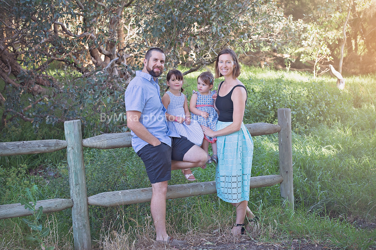Family of four in blue tones captured on fence ByMika family photographer