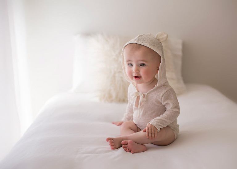 Baby Ella on bed with bear romper