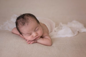 Newborn sleeping on hands with wrap